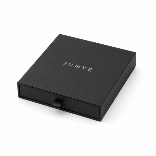 Closed black single-end drawer jewelry packaging box with a gold foil JUNYE logo and a ribbon pull on the front