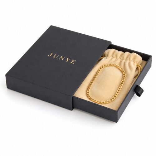 Black drawer box with the tray pulled out, holding a gold chain necklace on a velvet pouch