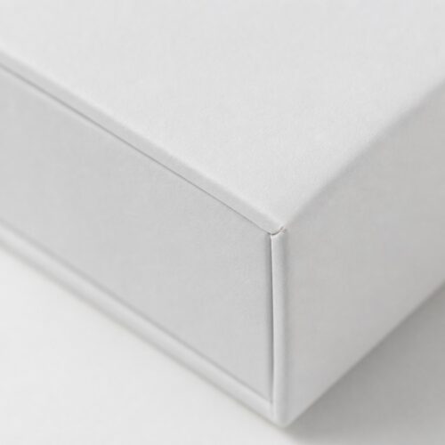 Corner detail of a white drawer box sleeve showing the tray seam and the folded edge