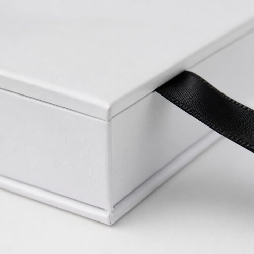Close up of the black satin ribbon on the front edge of a white flip box