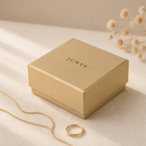 Gold lid and base jewelry gift box styled on linen with a gold chain and a ring