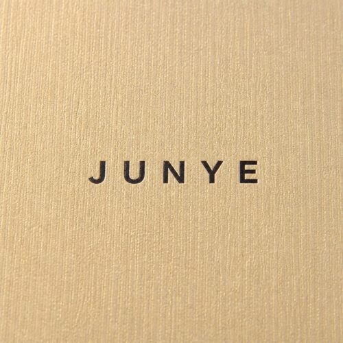 Macro of the gold fine textured specialty paper with the JUNYE logo printed on the lid