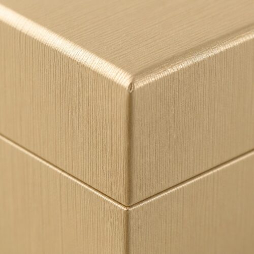 Corner detail of the gold rigid box showing the wrapped fold and the lid to base seam