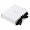 Closed white magnetic flip jewelry box with a black satin bow and a JUNYE logo on the lid