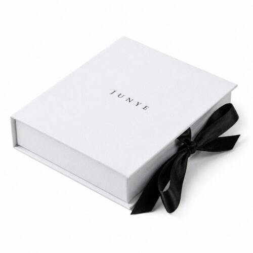 Closed white magnetic flip jewelry box with a black satin bow and a JUNYE logo on the lid