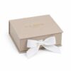 Beige flip jewelry box closed with a white ribbon bow tied at the front and the gold G.Z.JUNYE mark on the lid