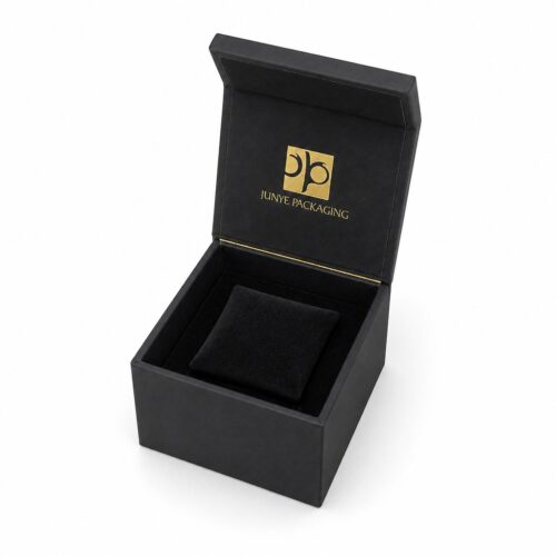 Black cube jewelry box with the magnetic flap lid open, showing the black flocked tray and raised centre cushion