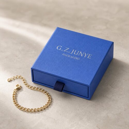 Blue square drawer jewelry box styled on stone with a gold chain bracelet beside it