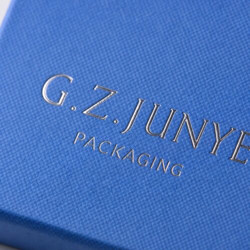 Close up of the gold G.Z.JUNYE stamp on the blue textured specialty paper of a square drawer jewelry box
