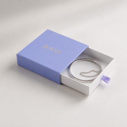 Silver bangle resting in the open white tray of a blue bracelet drawer jewelry box