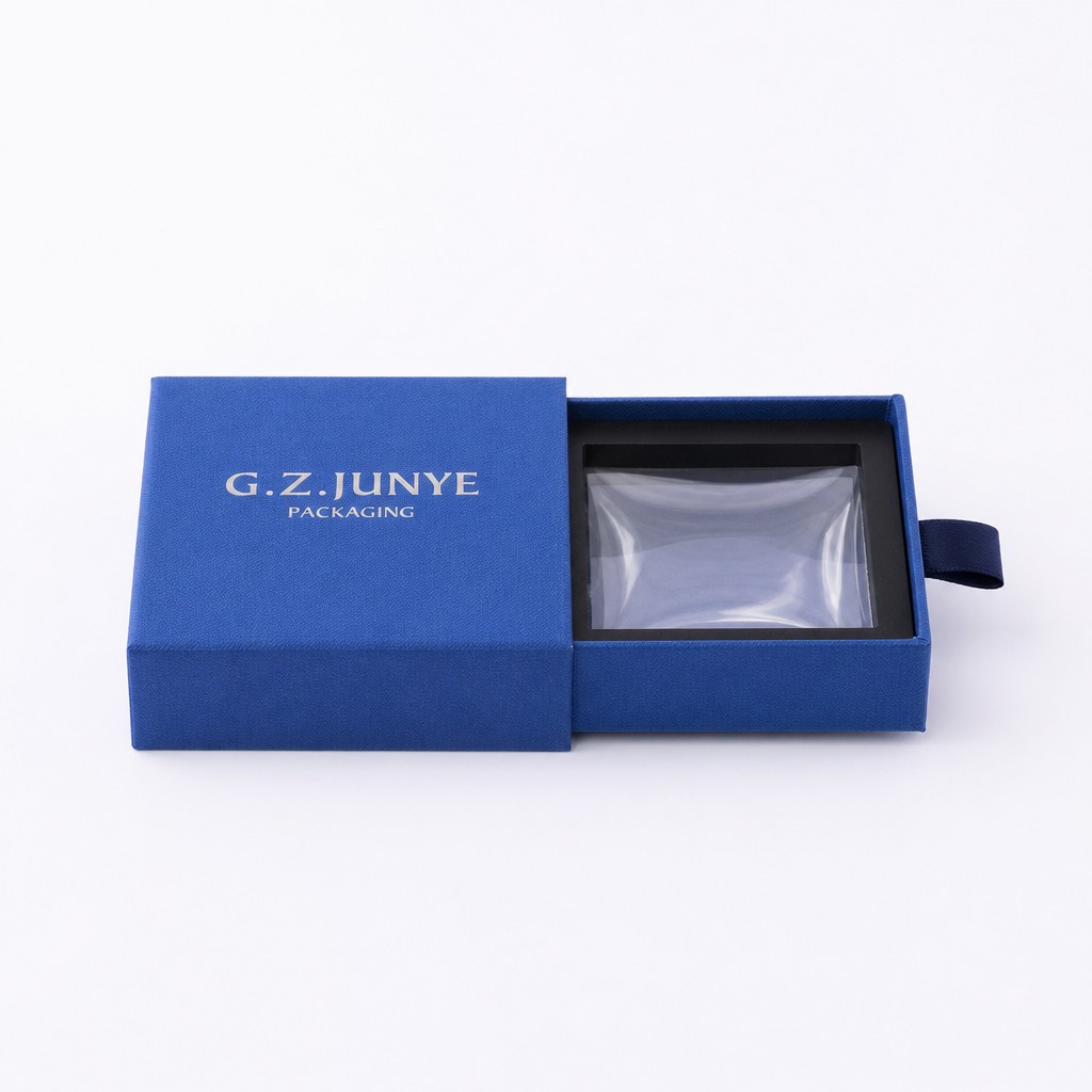 The tray of a blue square drawer jewelry box drawn out, showing the black blister frame with a clear bag over it