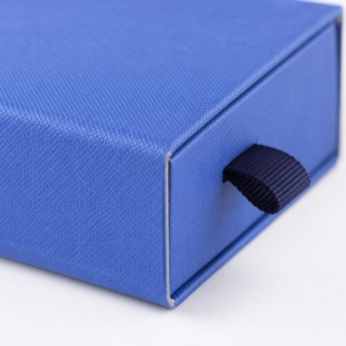 Detail of the navy ribbon pull and the wrapped sleeve corner on a blue square drawer jewelry box