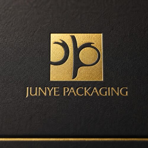 Close up of the gold foil JUNYE PACKAGING mark pressed into the matte black specialty paper of a cube box