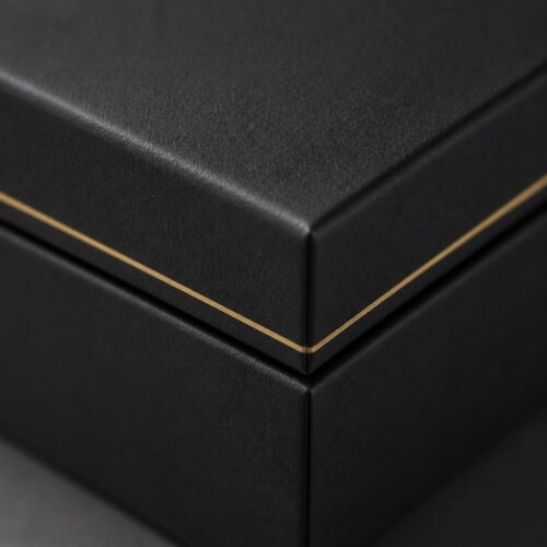 Detail of the gold foil hairline turning the corner at the seam of a black cube jewelry box