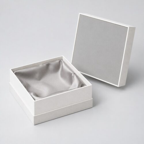 Lid lifted off the white gift box, satin lining falling in soft folds inside the base
