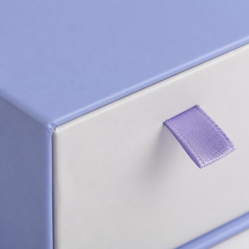 Satin ribbon pull on the tray face of a blue single drawer jewelry box