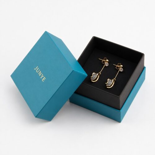Teal rimmed lid box open with the matte black base holding a gold pendant